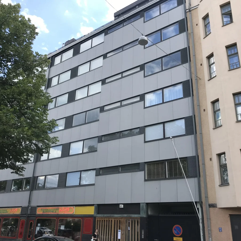Aleksis Kiven kadun concrete skin -julkisivu, puuritilällä verhottu ajoportti ja sisäänkäynti katutasossa, Helsinki
