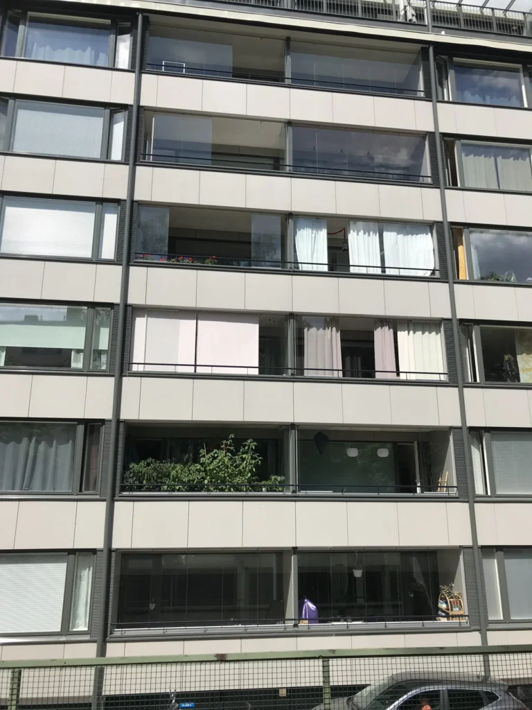 Aleksis Kiven kadun sisäpihan julkisivu, vaaleat concrete skin -levyt ja lasitetut parvekkeet, Helsinki
