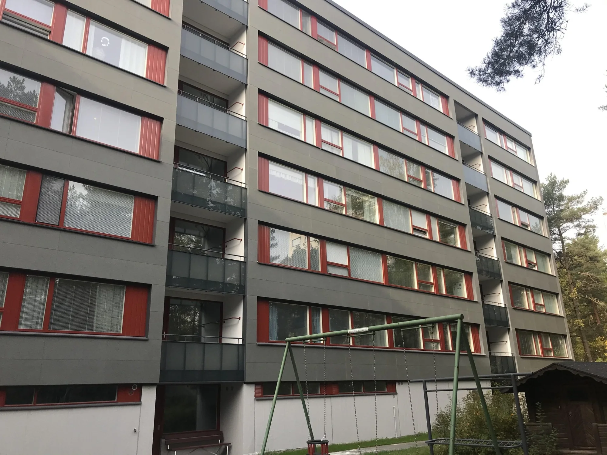 As Oy Nunnanhaka Turussa, harmaa julkisivulevytys, punaiset ikkunapuitteet ja pihan leikkialue Runosmäessä