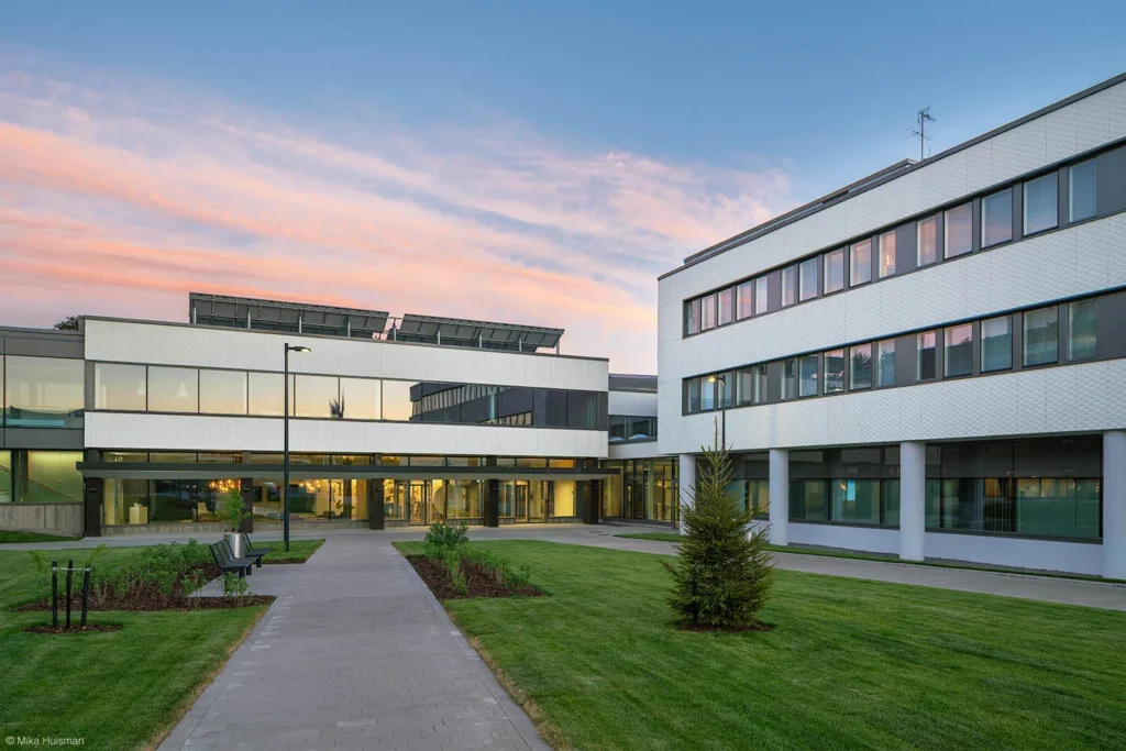 Fazerilan toimistorakennusten valkoiset ULMA Creaktive -julkisivut ja sisäpiha auringonlaskun aikaan, Vantaa