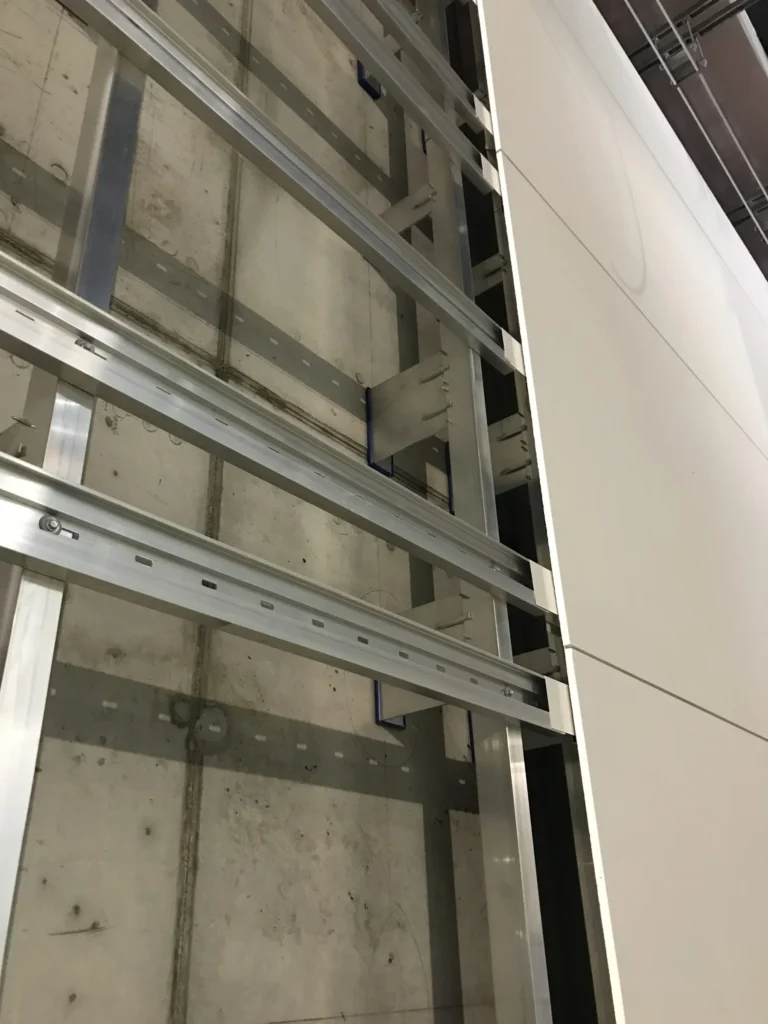 Kivenlahden metron Allface-alumiinirunko betoniseinalla, vaakaprofiilit ja kannakkeet, concrete skin -levyn reuna oikealla, Espoo