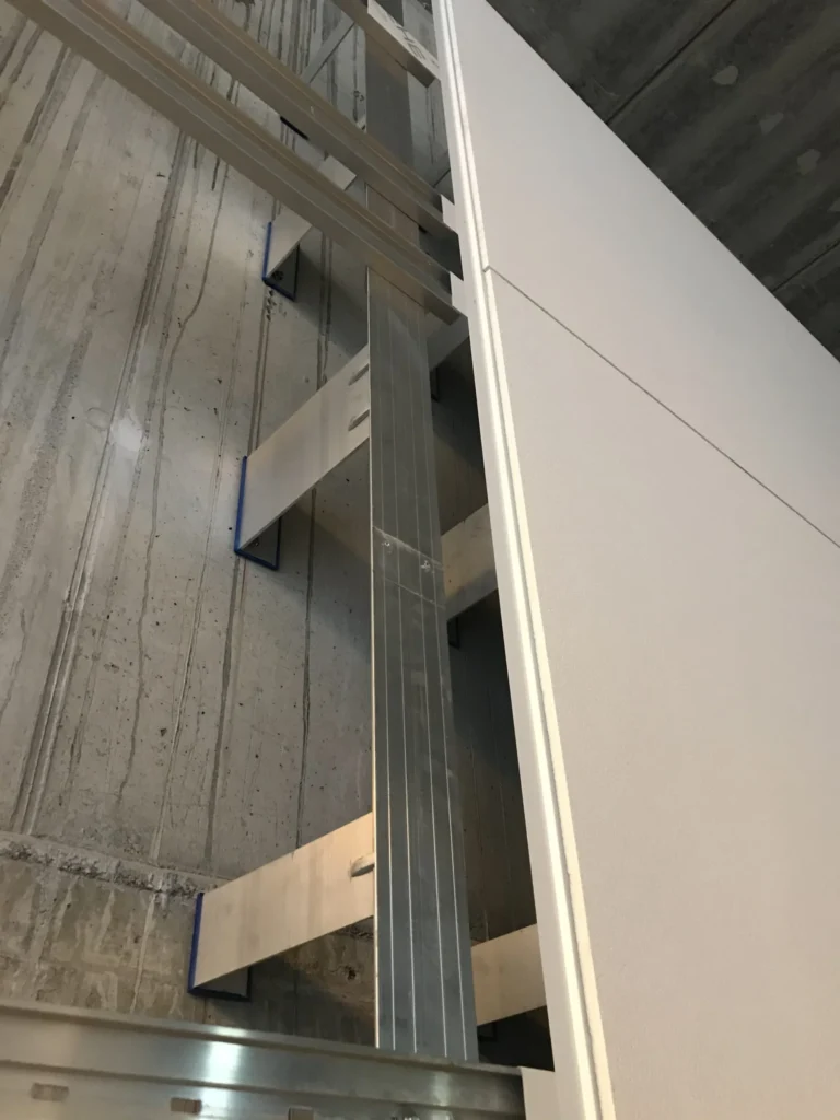Kivenlahden metron concrete skin -levyn reuna ja Allface-alumiinirunko betoniseinalla alhaalta kuvattuna, Espoo
