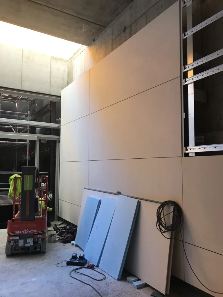 Kivenlahden metron concrete skin -julkisivua asennetaan, henkilonostin ja eristelevyt tyomaalla, Espoo