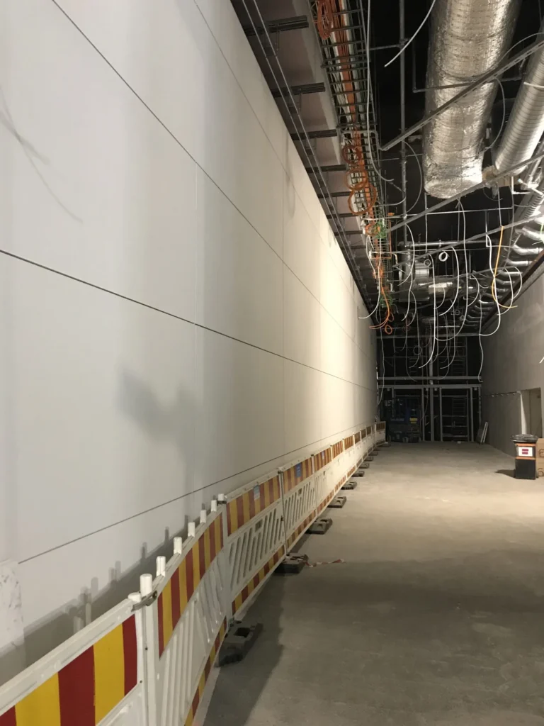 Kivenlahden metron pitka kaytavaseina concrete skin -levyilla, tyomaa-aidat ja talotekniikkaa katossa, Espoo