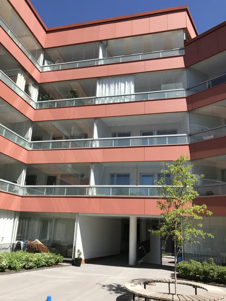 As Oy Koirasaarentie 36:n korallinpunainen concrete skin -julkisivu sisapihan lapiajon kohdalla, Helsinki