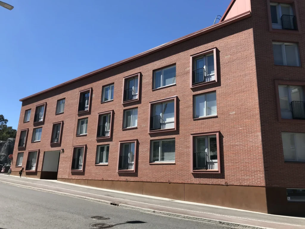 As Oy Koirasaarentie 36:n punatiilinen julkisivu ja concrete skin -ikkunapielet kadun varrella, Helsinki