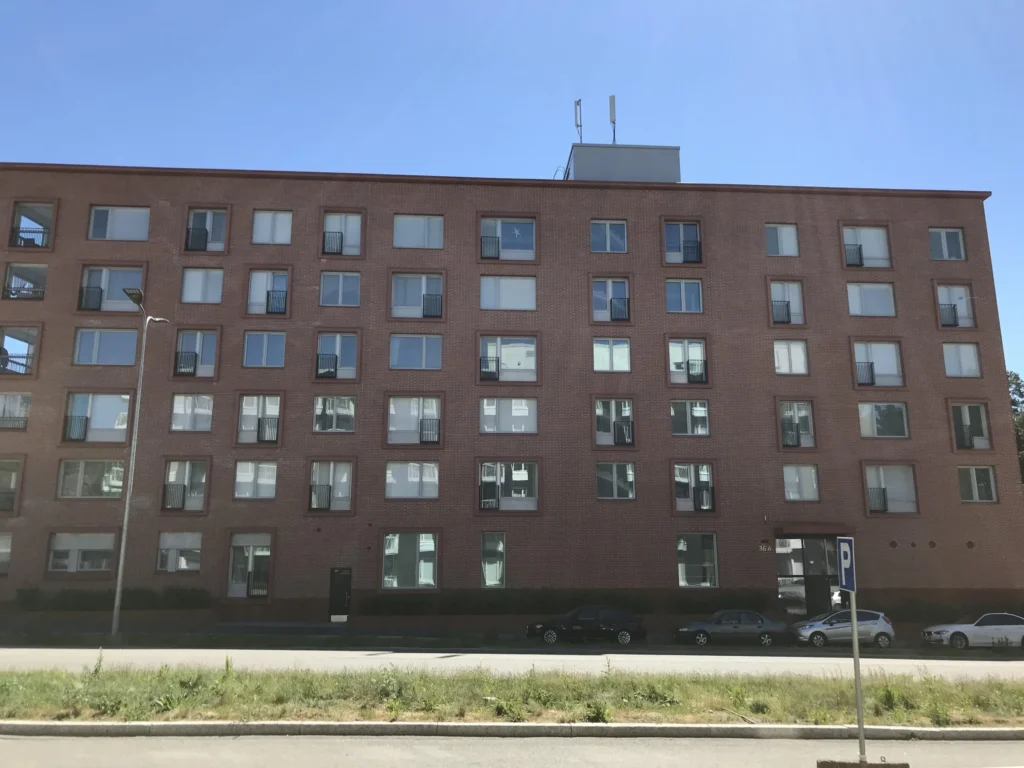 As Oy Koirasaarentie 36:n punatiilinen paajulkisivu concrete skin -ikkunapielineen kadulta kuvattuna, Helsinki