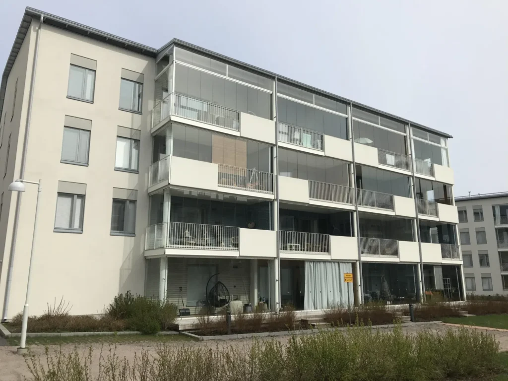 Luutnantinpolku 2:n asuinkerrostalon vaalea Concrete Skin -julkisivu, lasitetut parvekkeet ja pihan puolen näkymä