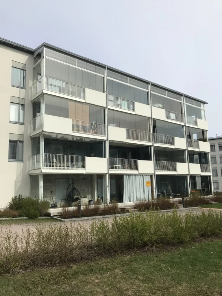 Luutnantinpolku 2:n asuinkerrostalon lasitetut parvekkeet ja vaaleat Concrete Skin -julkisivulevyt pihan puolelta