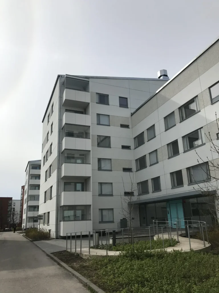 Kokonaisnäkymä Luutnantinpolku 2:n pihan puolelta, jossa näkyvät Concrete Skin -julkisivulevyt, lasitetut parvekkeet ja leikkialue
