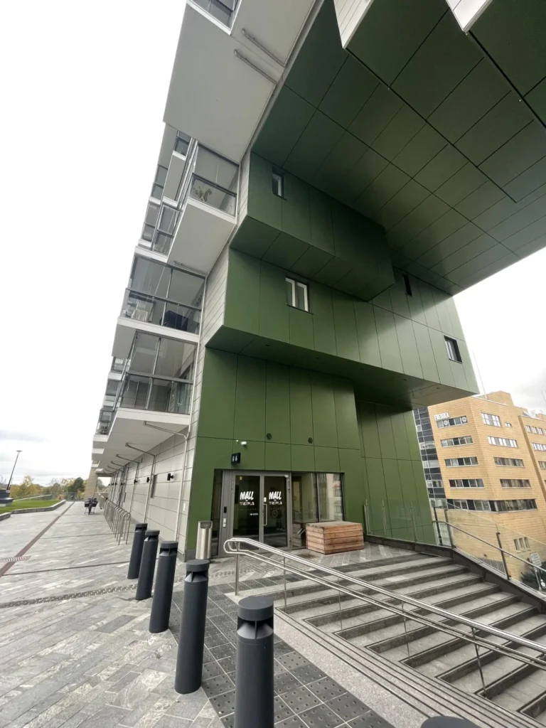 Mall of Triplan portaikko ja sisäänkäyntitasanne, vihreä ALUCOBOND julkisivu ja tummat pollarit kaupunkitilassa