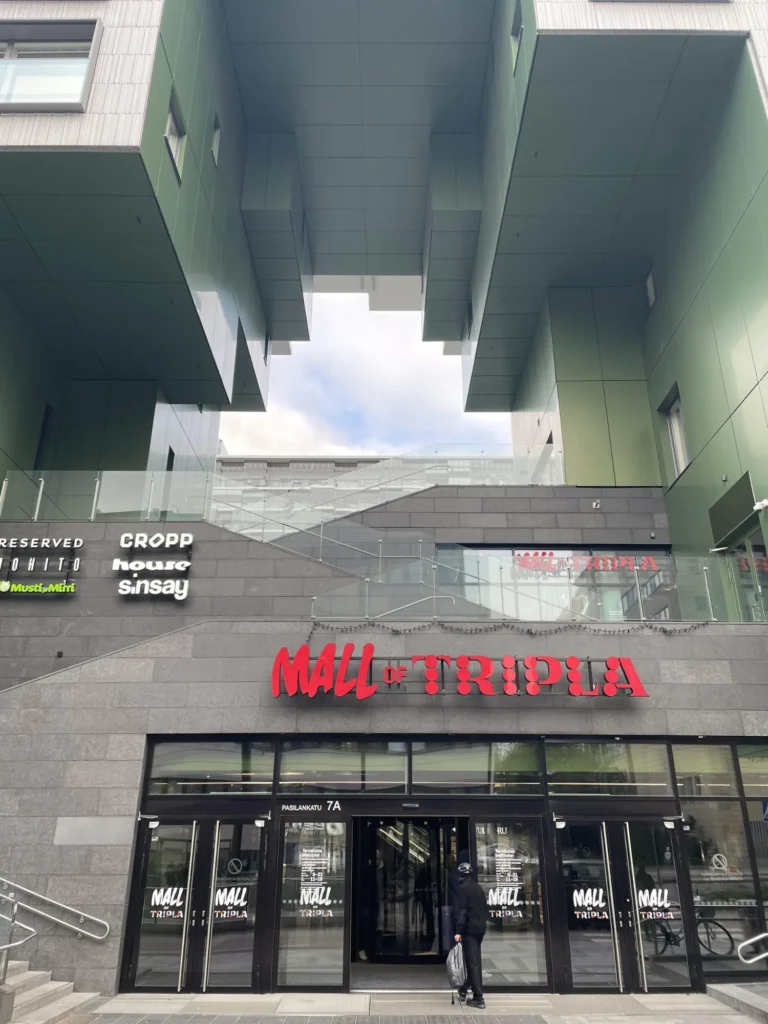 Mall of Triplan sisäänkäynti, punainen opaste, vihreä ALUCOBOND levytys ja lasikaiteet rakennuksen yläpuolella