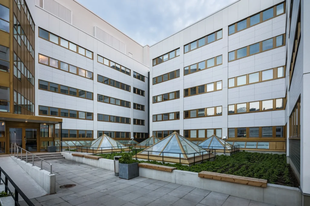 Ratamestarinkatu 9 sisäpiha, valkoiset klinkkerikuvioiset julkisivulevyt, lasiset kattolyhdyt ja kullanväriset ikkunat