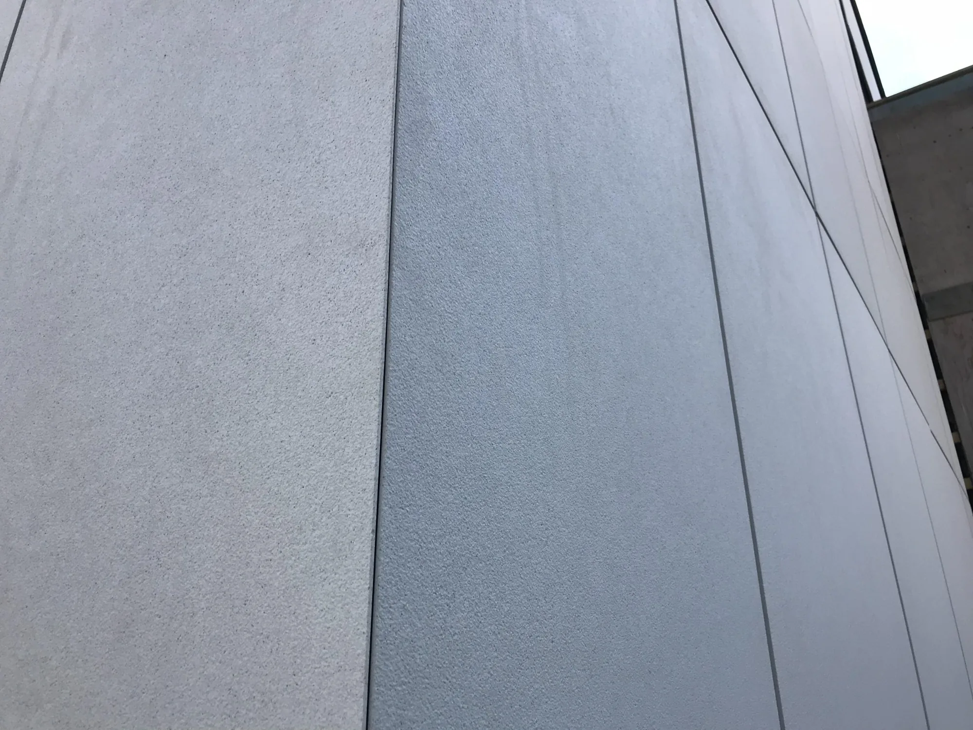 Syöpäklinikan vaalea concrete skin julkisivulevy lähikuvassa, hieno pintastruktuuri ja levysaumat