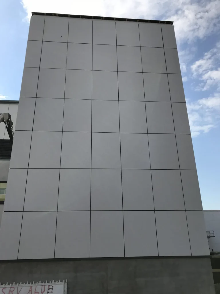 Syöpäklinikan vaalea concrete skin levyjako, korkea julkisivupinta ja pystysuuntainen rakennusosa