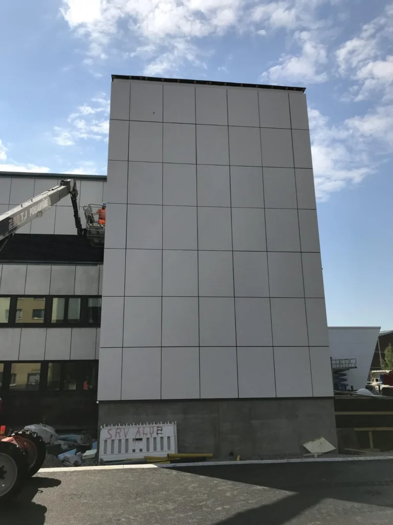 Syöpäklinikan korkea vaalea concrete skin julkisivupinta selkeällä levyjaolla