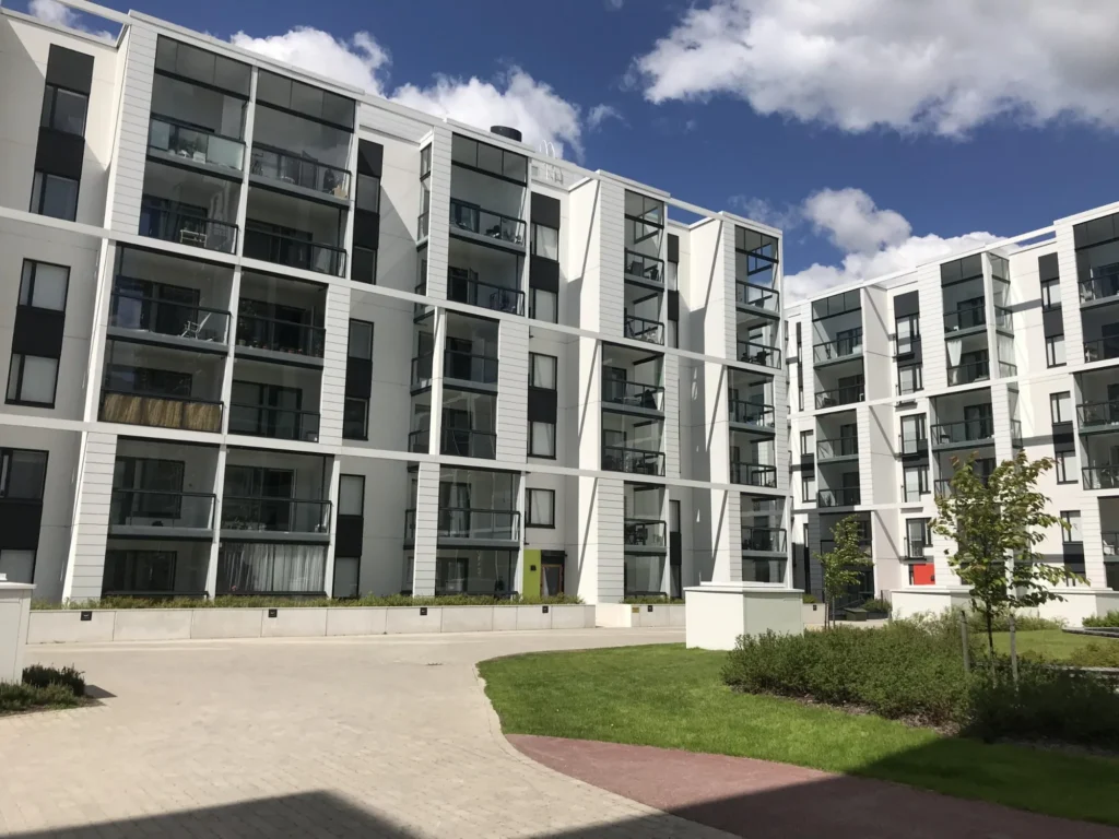 Valon korttelin sisäpihan rakennukset ja lasitetut parvekkeet, taustalla korkea tumma julkisivu